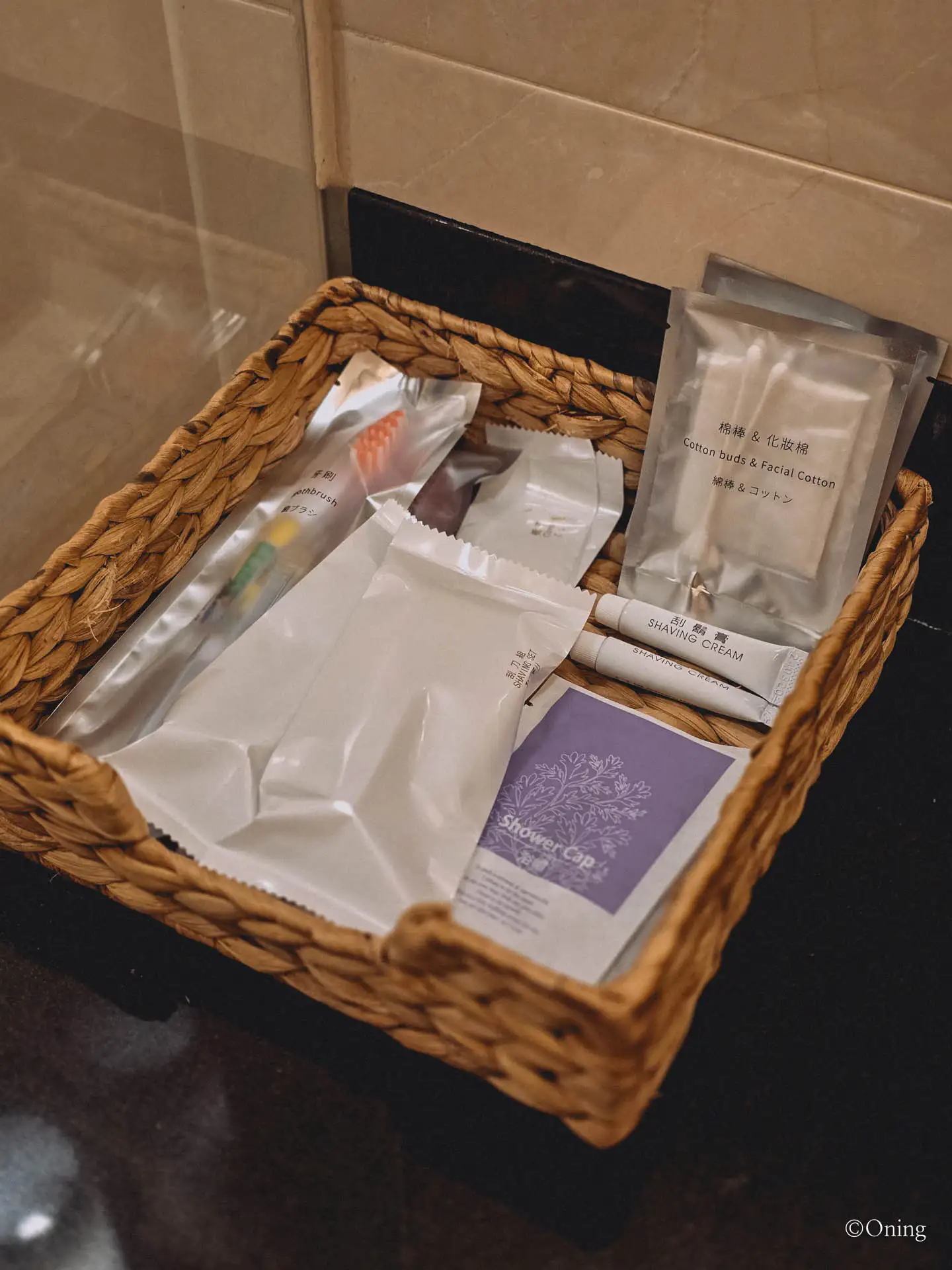 Basket of shower amenities including toothbrush, shaving cream and shower cap