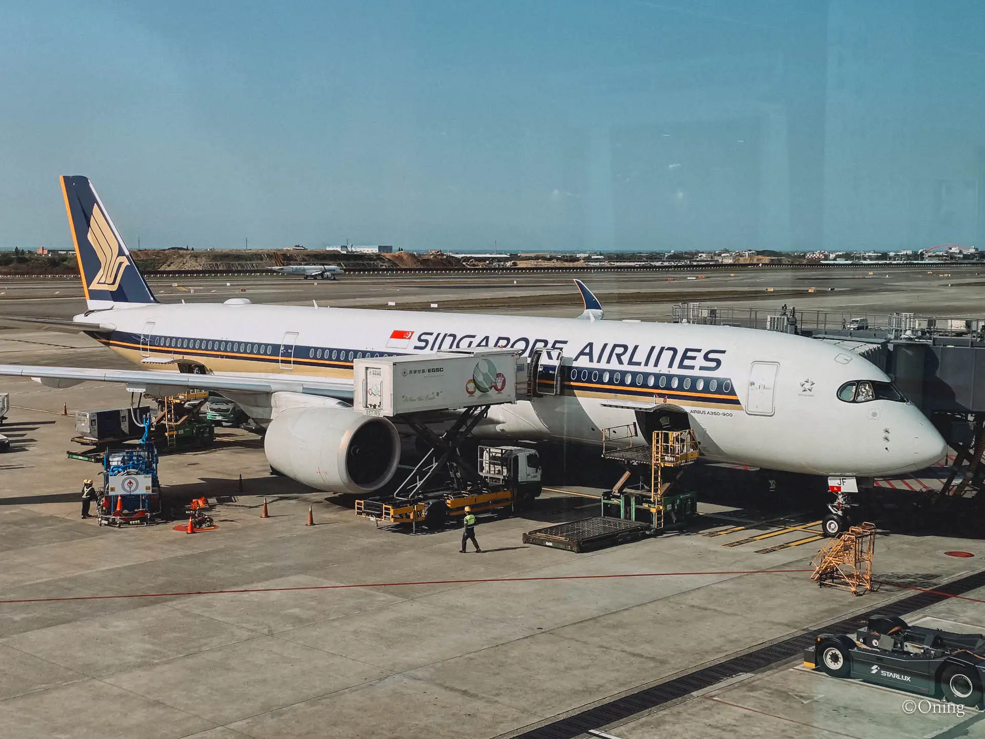 A Singapore Airlines Airbus A350-900 being catered at the gate, seen from the terminal window