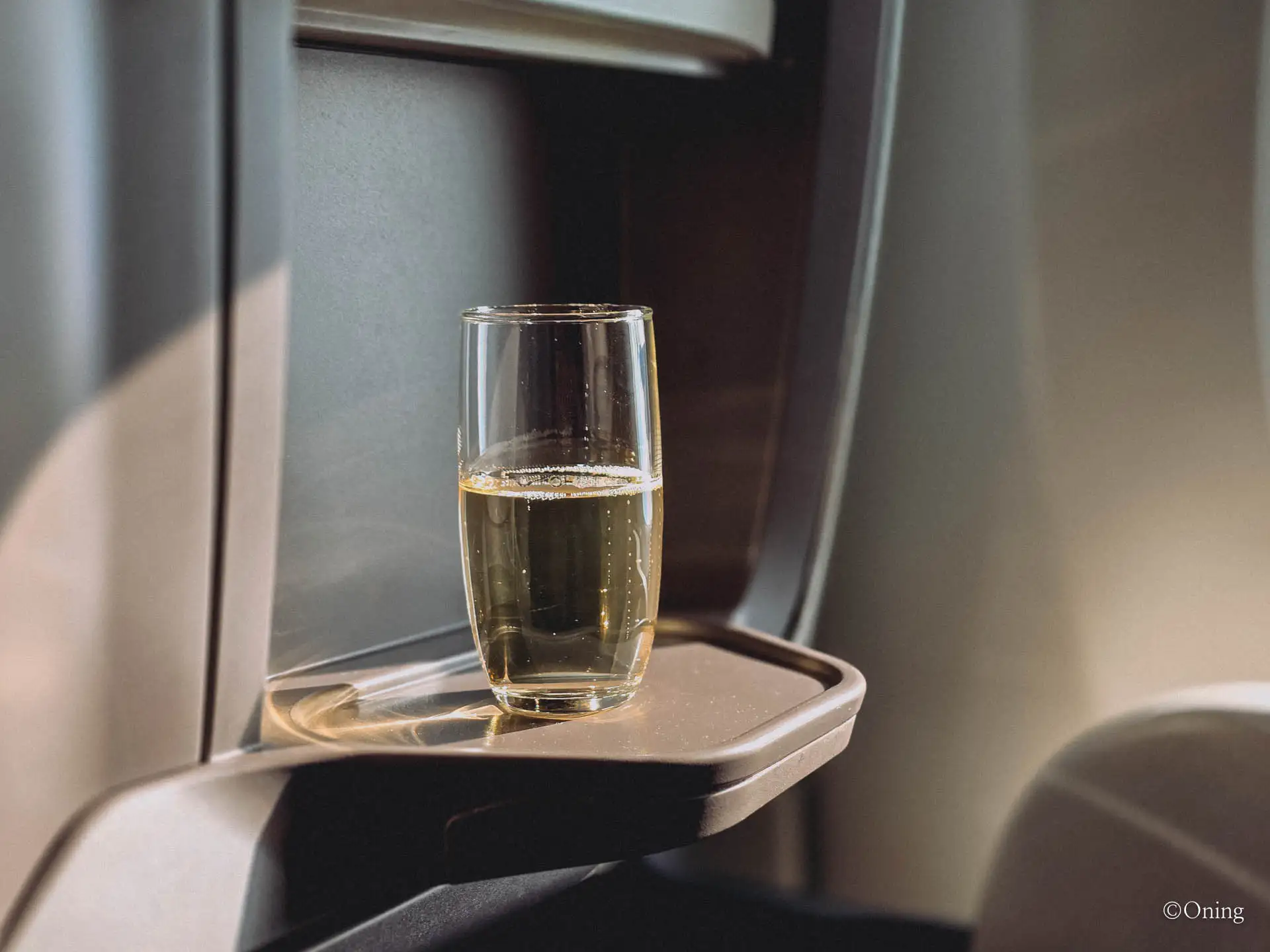Glass of champagne on a tray beside the cabin window in Singapore Airlines business class