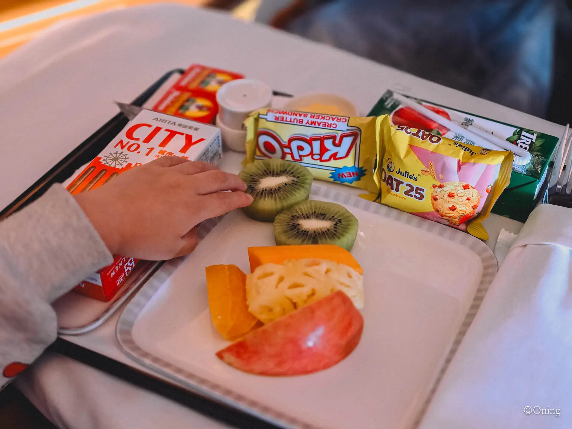 Kids' meal with kiwi, apple and orange alongside Kid-O and Julie's snacks
