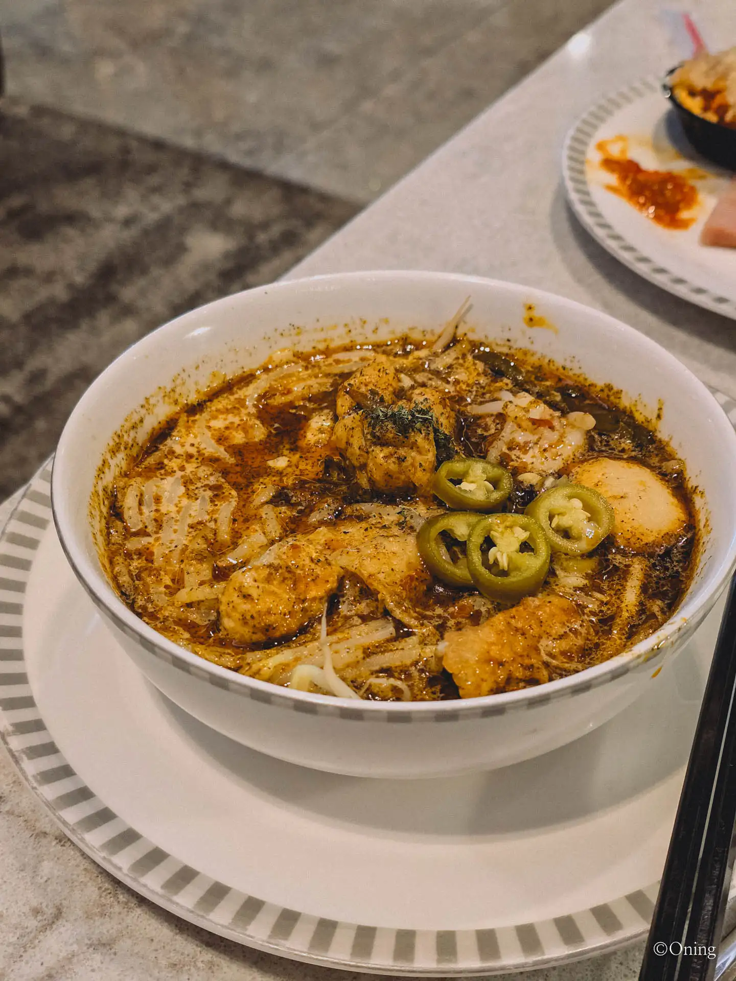 A bowl of laksa topped with green chili slices at the SilverKris Lounge