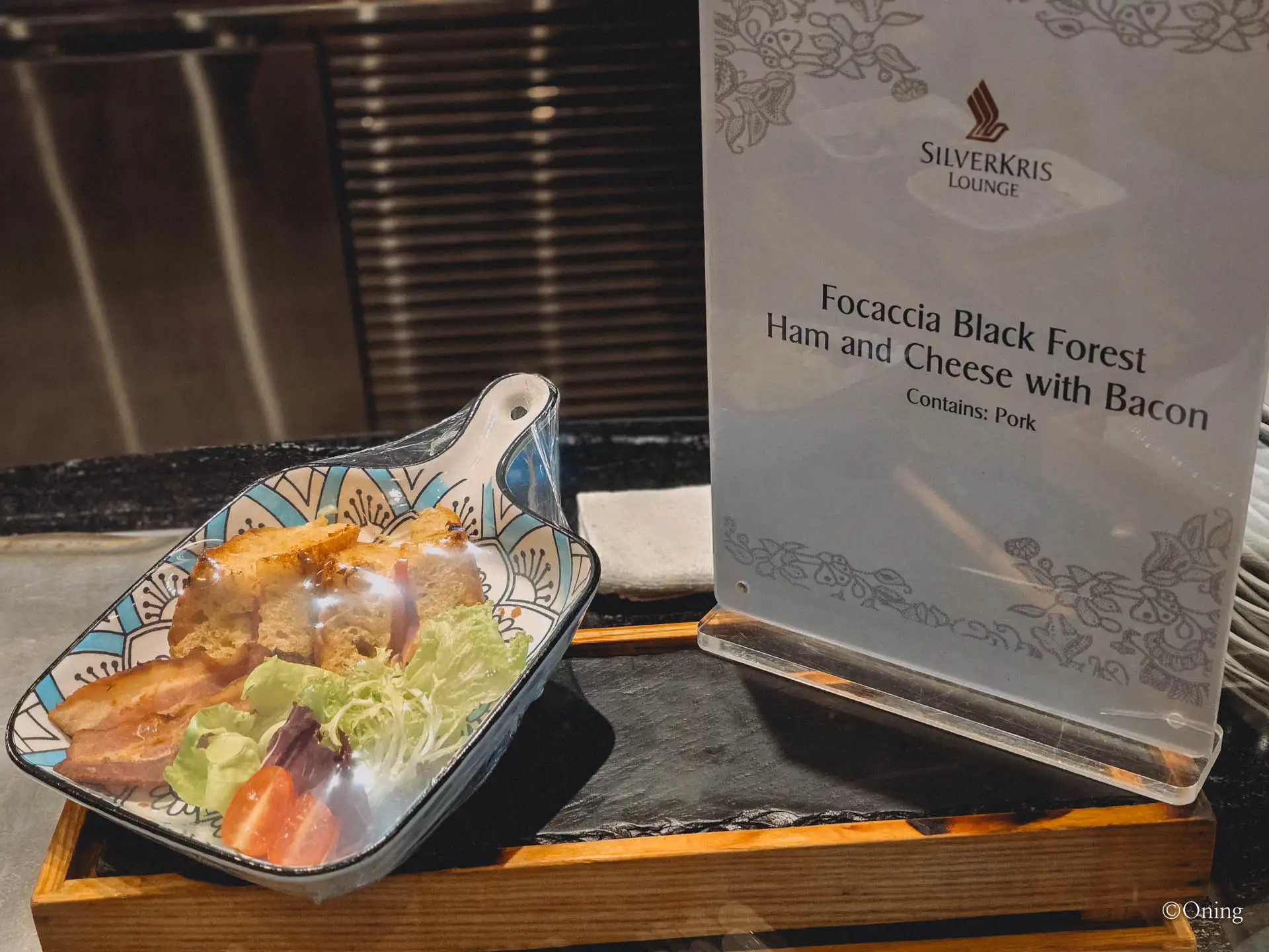 Focaccia with Black Forest ham, cheese and bacon beside a SilverKris Lounge menu card