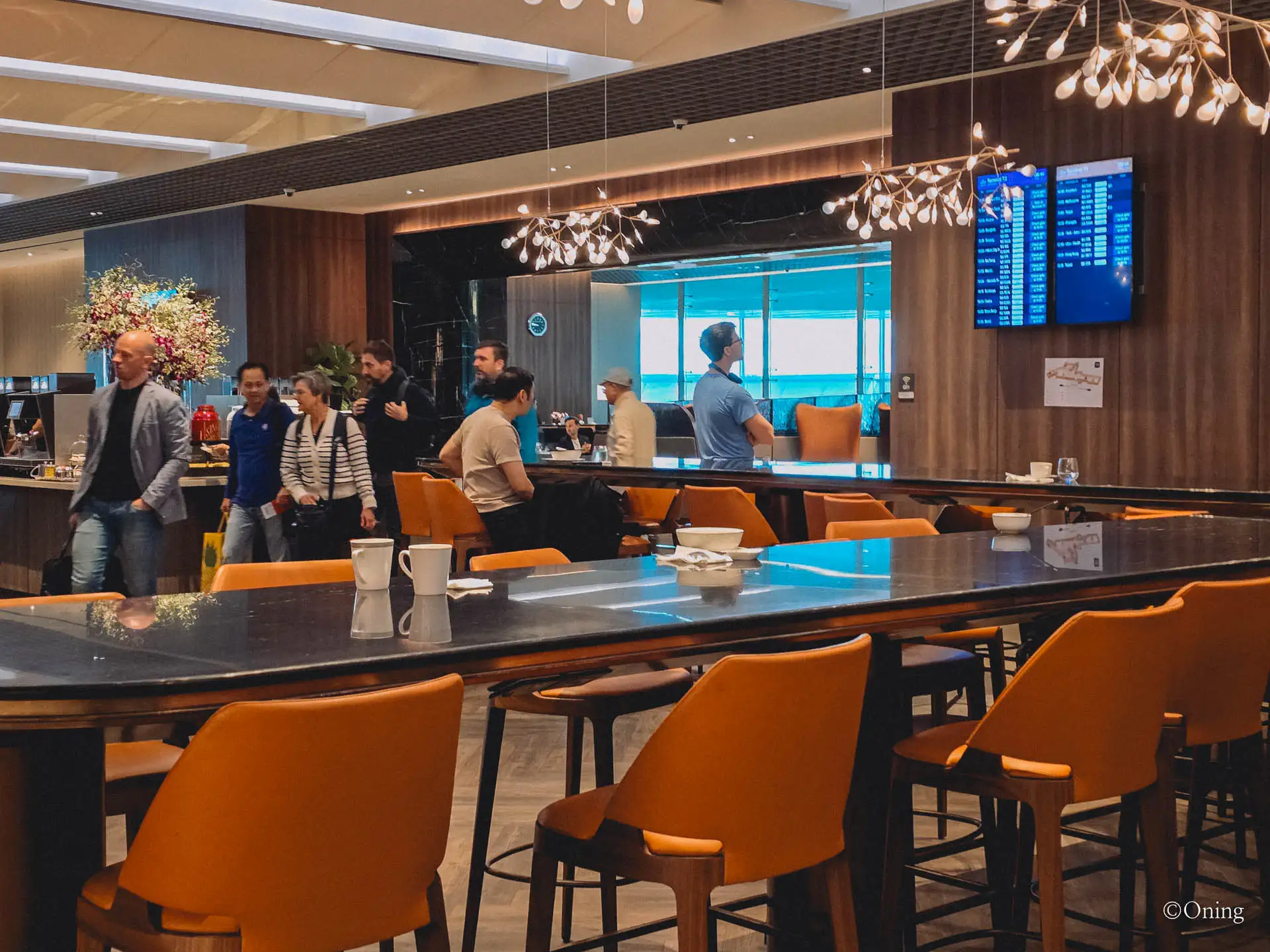 The busy main seating area with a bar and departures screen at the T3 SilverKris Lounge