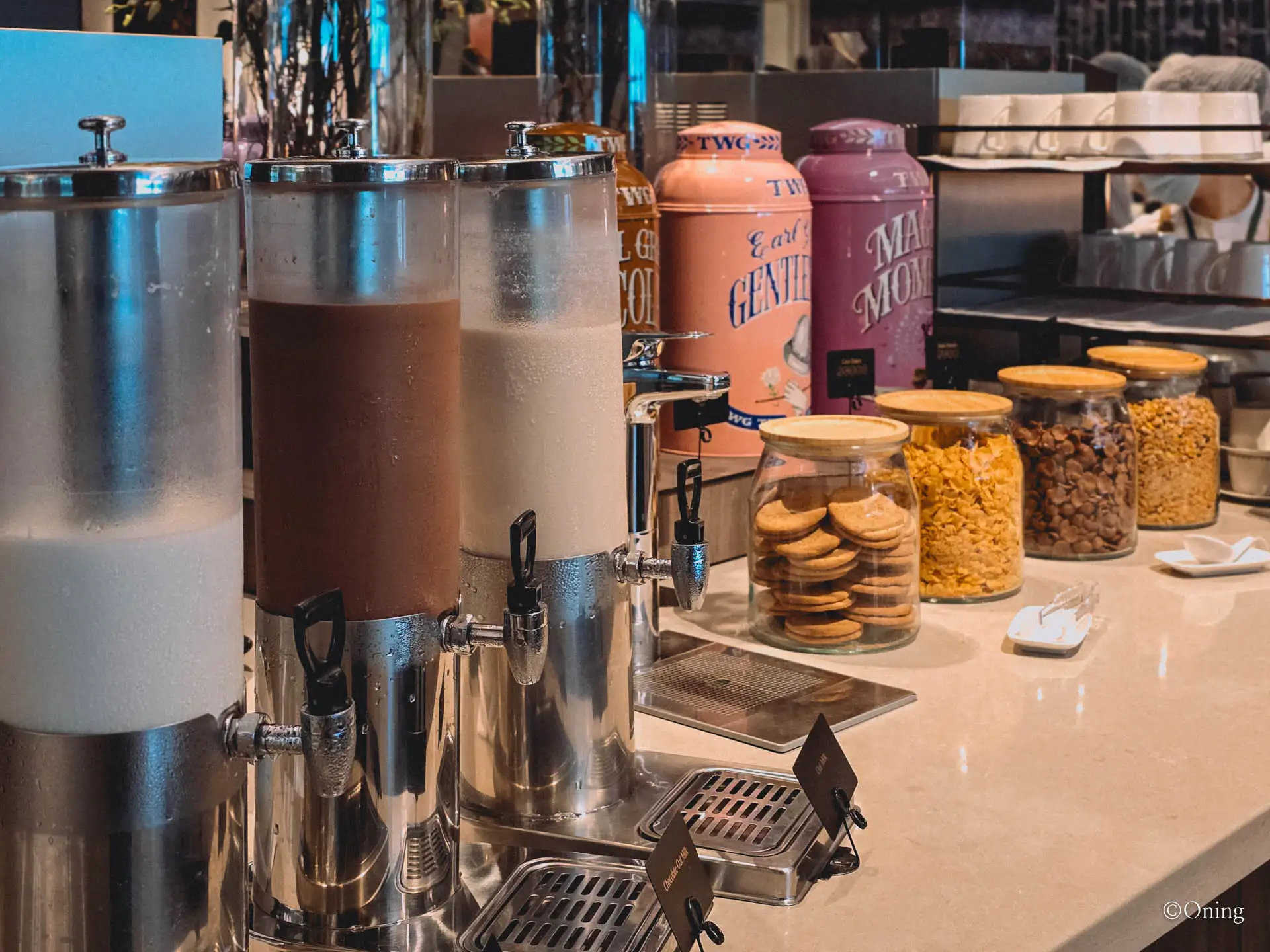 A beverage station with milk and juice dispensers, TWG teas and cereals
