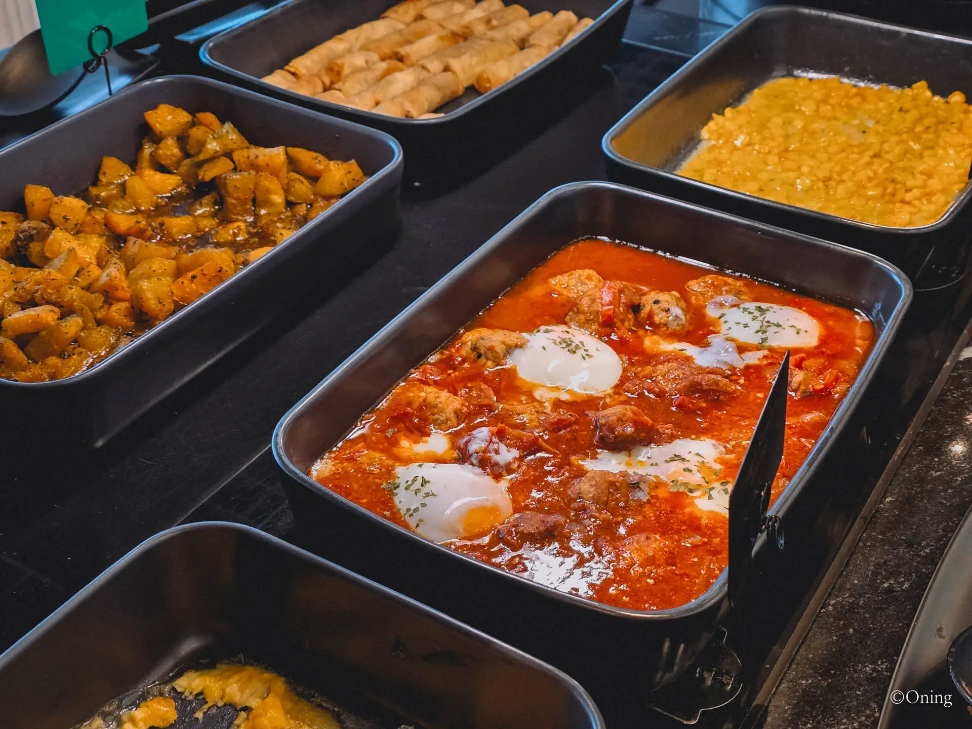 Shakshuka of eggs in tomato sauce beside pumpkin and dhal at the lounge buffet