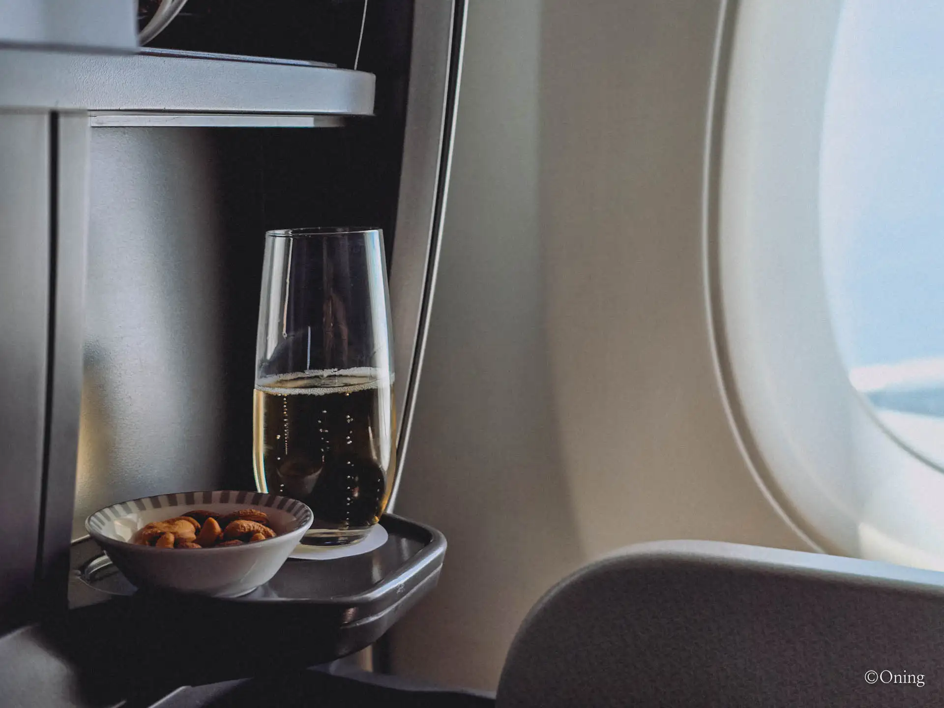 Welcome champagne and a bowl of nuts by the window in Singapore Airlines business class
