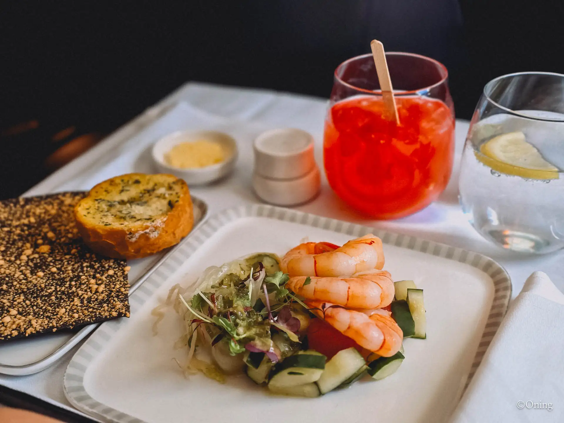 Shrimp salad with garlic bread, a cheddar cracker and a Singapore Sling on the tray