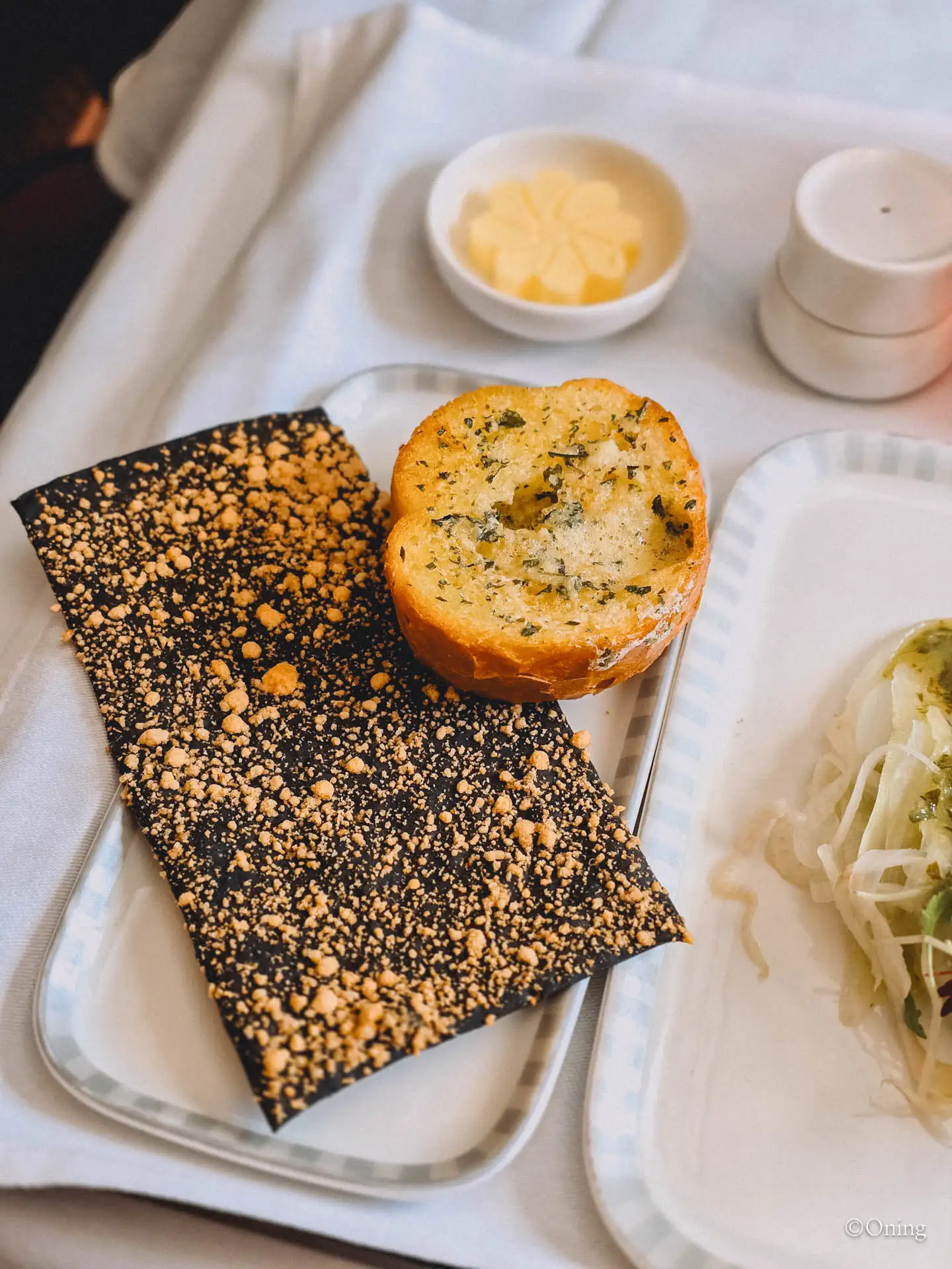 Garlic bread and a black sesame cheddar cracker on a Singapore Airlines business class tray